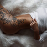 Schöner weiblicher Körper mit einem stilvollen Vintage-Tattoo am Oberschenkel.
