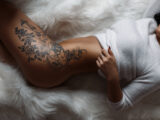 Schöner weiblicher Körper mit einem stilvollen Vintage-Tattoo am Oberschenkel.