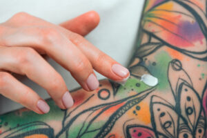 Finger tragen Creme auf die Haut, auf ein Tattoo, auf. 
