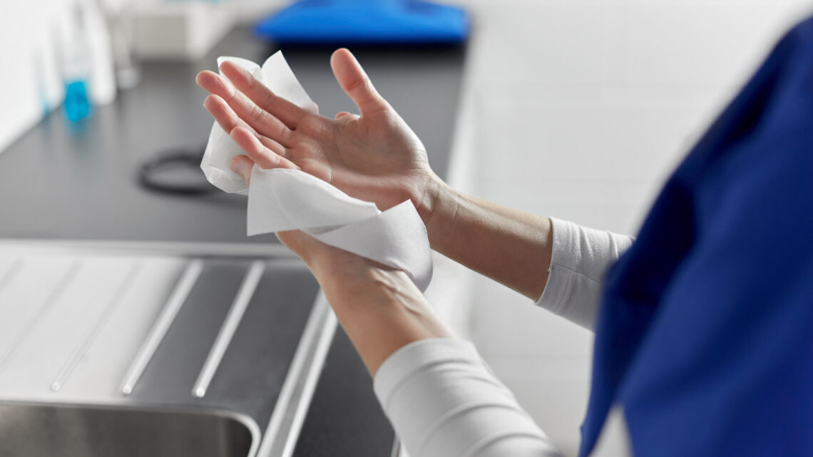 Hygiene-, Gesundheits- und Sicherheitskonzept - Nahaufnahme einer Ärztin oder Krankenschwester, die im Krankenhaus die Hände mit Desinfektionstüchern trocknet.